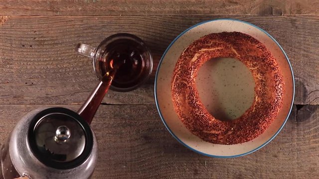 top view of Pouring turkish tea into the cup with teapot and turkish simit on the table
