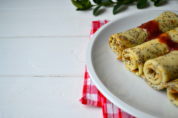 Traditional Russian and Ukrainian this pancakes with poppy seeds and strawberry jam on a white plate. National food for Maslenitsa.
