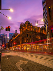 Fototapeta na wymiar Sydney, Australia - 28 Feb 2020: A tram travels past the historic Queen Victoria Building during dusk. Landmark historic building which features a retail complex inside.