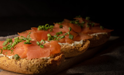 Whole toast with cheese spread and smoked salmon on wooden board