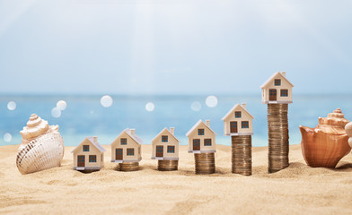 House Models Arranged On Stacked Coins At Beach