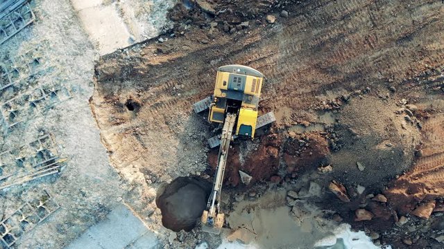 Soil is getting extracted from underground by the digging vehicle. Heavy industrial equipment working.