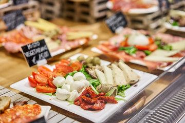 vegan menu. Light Italian snacks. Cheese plate with tomatoes and olives. Delicious cheese mix on wooden plate. Street food market in Florence, Italy.