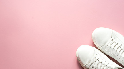 Sneakers white over pastel pink   background with top view and copy space. A fashionable but also sporty background. FLATLAY