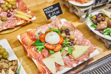 Meat plate, delicacy and Anantipasto. Salami, roast beef, Parma ham, smoked duck breast. Various snacks and antipasti on the table. Street food market in Florence, Italy.