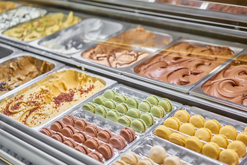 Assortment of colorful macaroons on cafe showcase. Variety of macaron flavours. Sweet almond cakes in store. Italian gelateria.