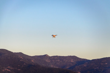 A drone flying against blue sky and mountains on dusk