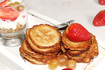 Pancakes with berries, strawberries and grapes, on a sunny sunny background. The concept of healthy and natural food. Healthy breakfast, food for children. selective focus.  Shrovetide