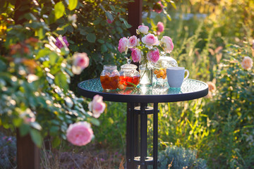 Jam in glass jar. Romantic dinner in the garden under a rose bush Pierre de Ronsard. Summer time