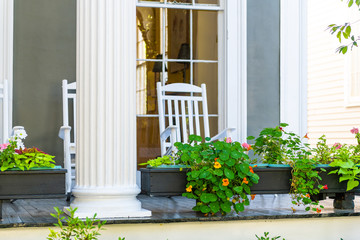 Historic Garden district in New Orleans, Louisiana with patio garden green plants flowers on white antebellum column and rocking chairs on old street