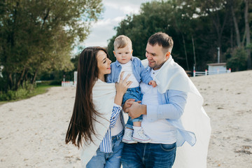 Young family having fun together on the beach by the lake.