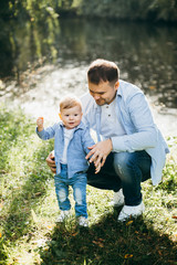 Fototapeta premium Happy young family spending time together outside in green nature near the water.