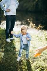 Happy young family spending time together outside in green nature near the water.