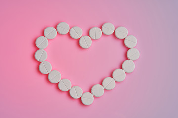 Medicines for the heart lie on a pink background. Heart pills and a bottle lie on a hot pink background.