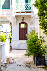 Fototapeta premium Seaside white beach door wood architecture and path way with green landscaping shrubs bushes on sunny day