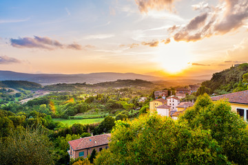 Fototapeta na wymiar Colorful evening sunset in small town of Chiusi, Tuscany Italy with houses roof rooftops on mountain countryside rolling hills landscape and picturesque cityscape with sun