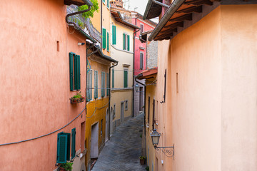 High angle aerial view on Chiusi, Italy street narrow alley in small historic town village in Umbria on sunny day with orange yellow bright vibrant colorful walls, windows shutters - Powered by Adobe