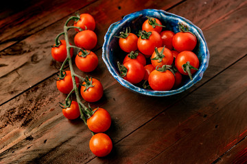 Fototapeta na wymiar tomates cherry en tabla de madera cuchillo de chef y vegetales ajo cebolla tomillo y pimiento con mantequilla 