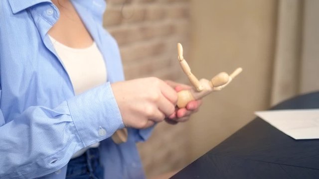 beautiful brunette girl draws a sketch with a wooden mannequin