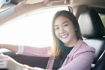 Asian female driver smiling and drinking coffee in the car, Beautiful girl  holding an eco paper coffee cup,looking to camera while driving her car, happy life transport in city