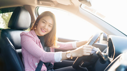 Beautiful Asian Business woman sitting on car seat and fastening seat belt, car safety belts concept.