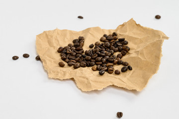 Coffee beans isolated on kraft paper with space for text. Roasted coffee beans as background. Flat lay, top view, copy space