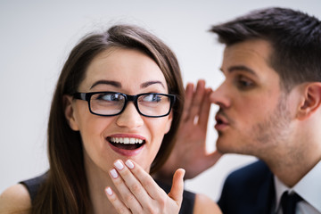 Businessman Whispering Into Female Partner's Ear