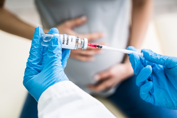 Doctor Preparing Vaccine Injection For Pregnant Woman At Clinic