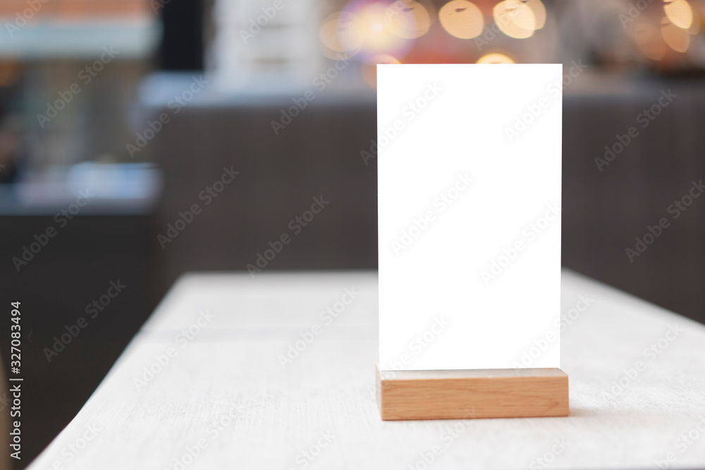 Wall mural Mock up Label the blank menu frame in Bar restaurant ,Stand for booklets with white sheets paper acrylic tent card on wooden table cafeteria blurred background can inserting the text of the customer.