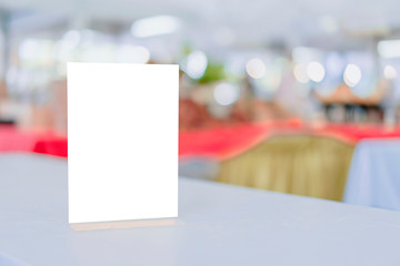 Mock up Label the blank menu frame in Bar restaurant ,Stand for booklets with white sheets paper acrylic tent card on wooden table cafeteria blurred background can inserting the text of the customer.