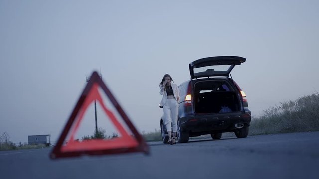 View of triangle sign on roadway in front of worried woman flustering at car