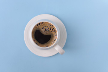 Top view of Coffee in cup with foam on a blue background