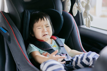 Asain baby crying little girl on the car seat in the car before going to school ,Preschool cute 2 years old sitting in safety car seat,bad mood, negative emotion, upbringing and family concept