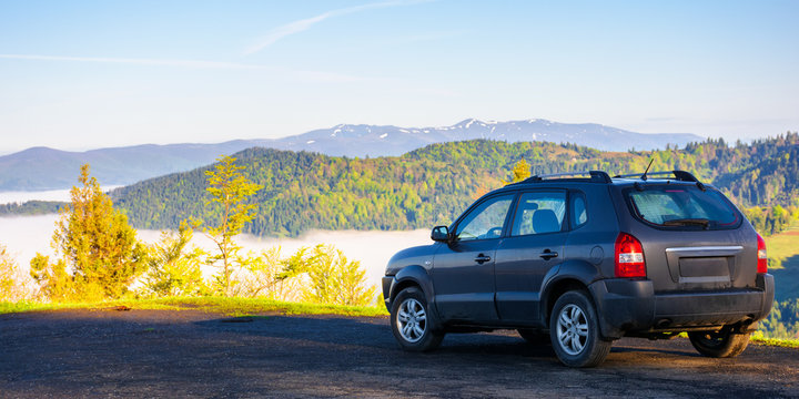 suv on the edge of a mountain. beautiful view in to the distant valley full of fog. ridge in the distance. fantastic springtime scenery in the morning. travel by car concept