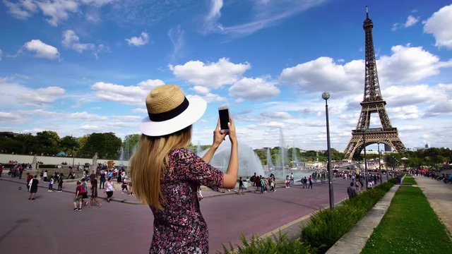 Beautiful elegant tourist woman taking picture of Eiffel Tower on smartphone camera. Exploring Paris.