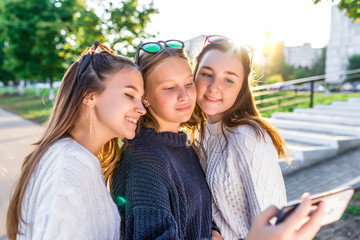 3 girls teenagers 12 13 14 years, summer park, holding smartphone hands, selfie photo. Holiday weekend, best friends, emotions of happiness fun smile. Social networks on Internet, online application.