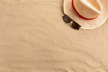 Fototapeta na wymiar Straw hat and sunglasses, on sand background. Beach vacation concept .Top view with copy space.
