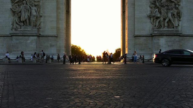 Visitors taking photos of sunset light in Paris, under Arc de Triomphe. Tourism attraction & famous landmark. Economic and business city in Europe.