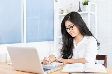 Education study abroad, Overseas Asian student girl sitting at table looking book while do homework...