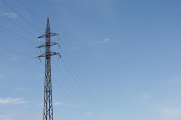 High voltage power line against a blue sky with a cloud