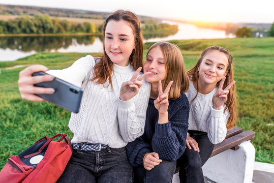 3 girls teenagers 12 13 14 years, summer , holding smartphone hands, selfie photo. Holiday weekend, best friends, emotions of happiness fun smile. Social networks on Internet, online application.