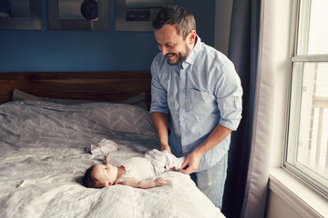 Middle age Caucasian father changing diaper clothes for newborn baby daughter son. Man parent...