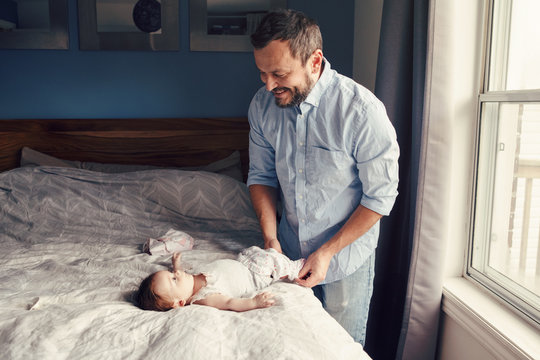 Middle age Caucasian father changing diaper clothes for newborn baby daughter son. Man parent taking care of a child at home. Authentic lifestyle candid moment. Single dad family day life.