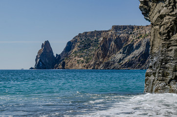 Mountain seascape. Vertical rock on which a wave rolls. Beach, recreation, tourism, travel.
