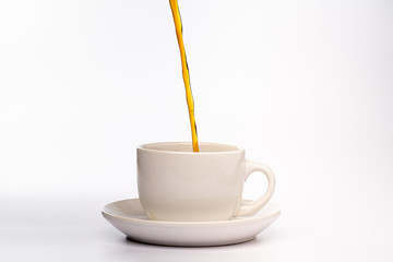 Coffee pouring into a white cup isolated against a plain white background