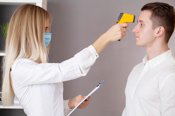 Doctor measures the patient's temperature with a laser thermometer