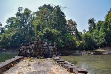 Fototapeta na wymiar walkway leading to ancient temple ruins surrounded by lake and water in angkor wat, cambodia