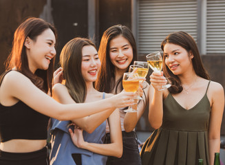 young beautiful happy asian women holding bottle of beer chat together with friends