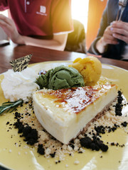 Closeup homemade cheese cake served with matcha and oange  ice cream and whipping cream.