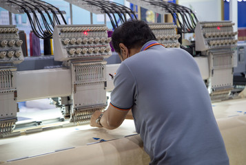 Worker set up embroidery machine in garment industry